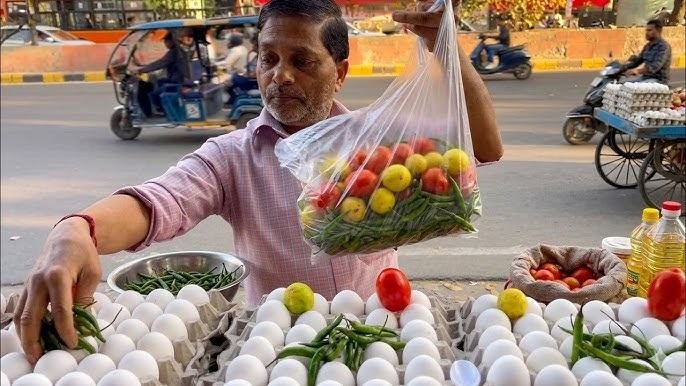 A street vendor arranging eggs, vegetables and fruit at a market stall