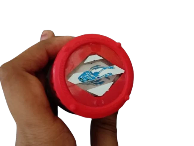 The red cap held up to the camera with the picture window visible