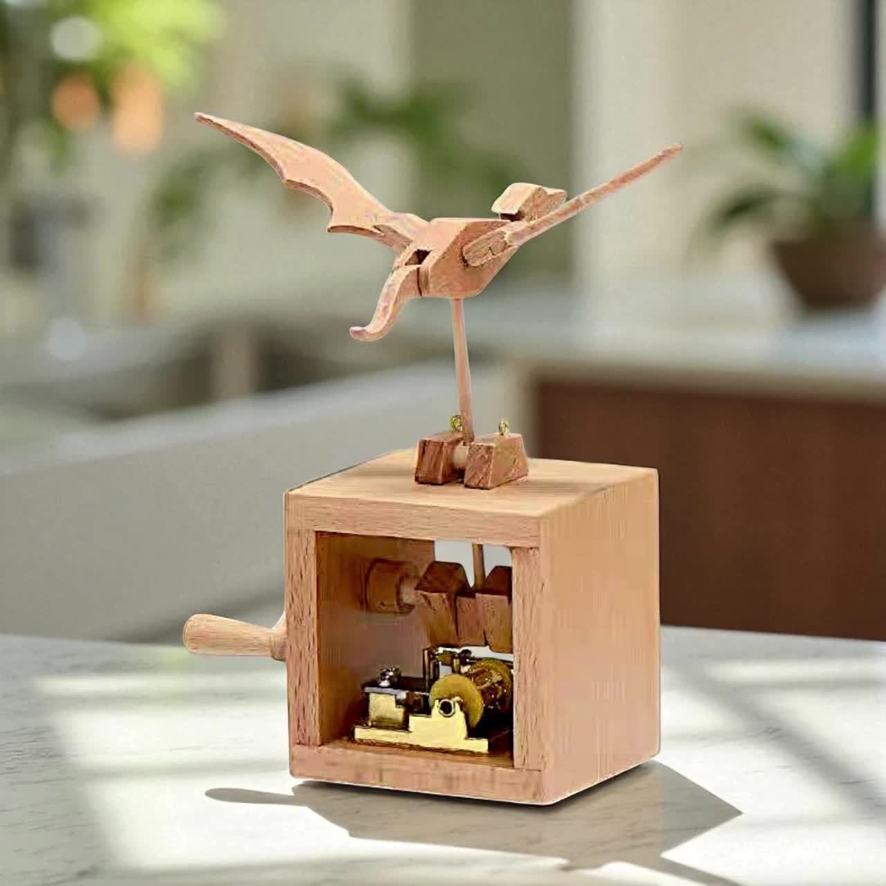 A wooden winged creature automaton on a box with a side handle