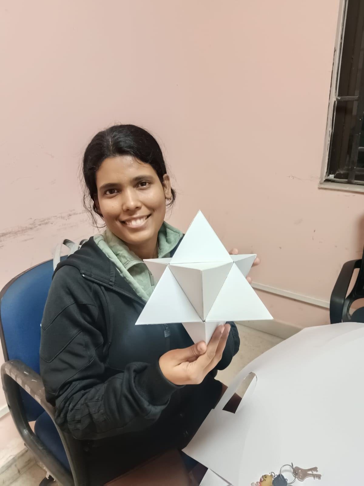 Holding up a white paper model of the stellated octahedron